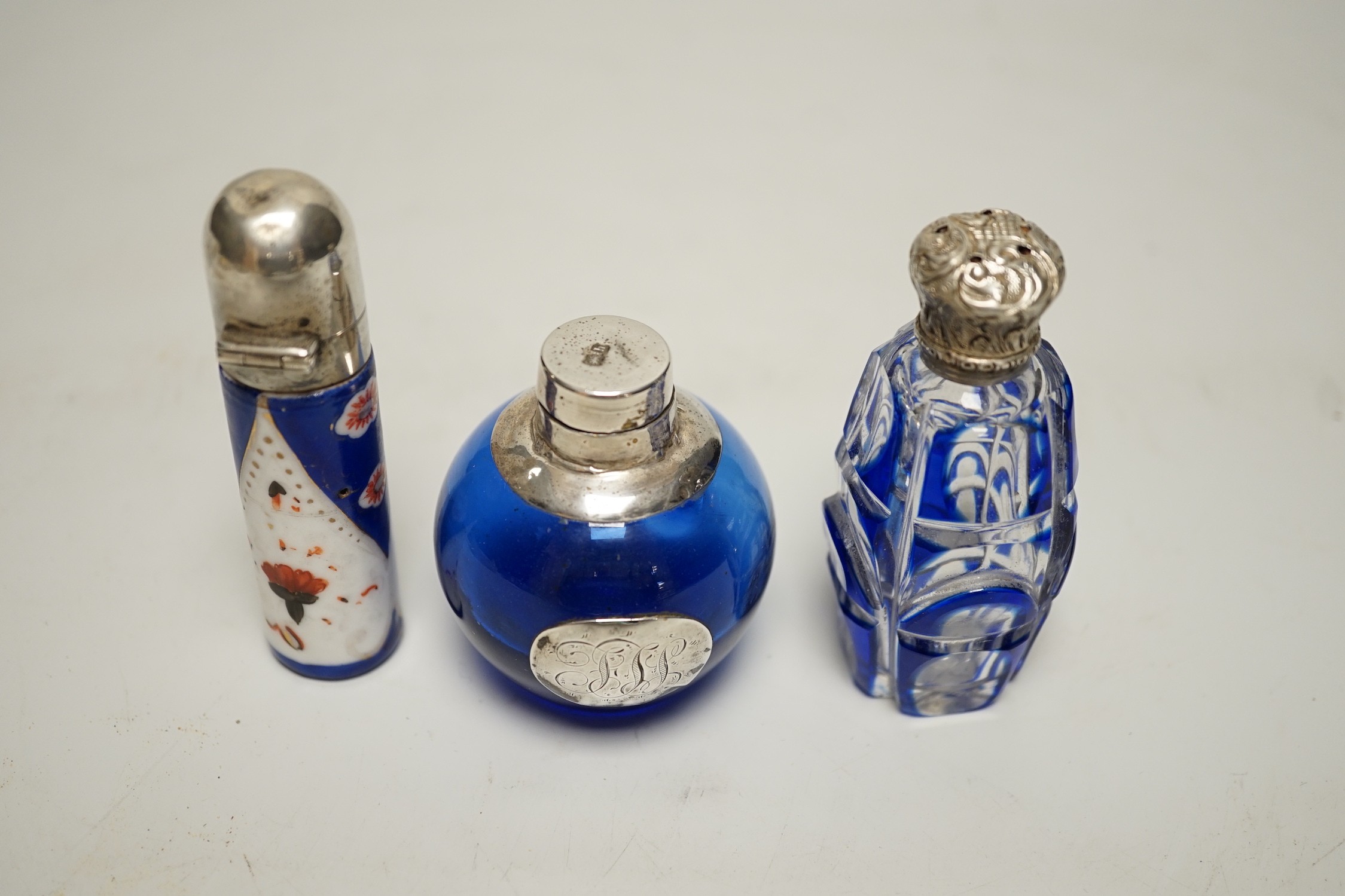 Three assorted silver or white metal mounted glass or porcelain scent bottles, tallest 78mm.